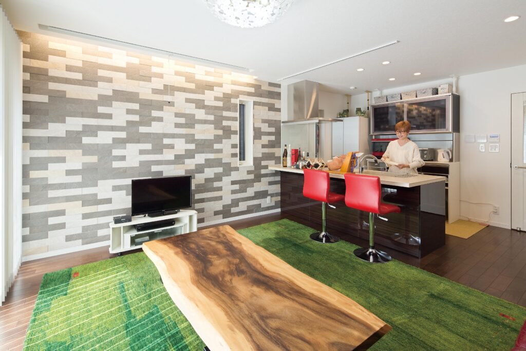 手話サロンとしても活躍する1階リビング。コミュニケーションが弾む対面式キッチンや、インパクトのあるエコカラット、遊牧民がつくったギャッベのカーペット、モンキーポッドのテーブルなどこだわりを満載。