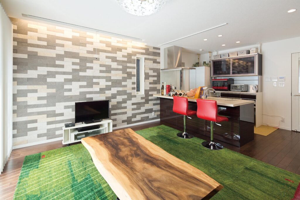 手話サロンとしても活躍する1階リビング。コミュニケーションが弾む対面式キッチンや、インパクトのあるエコカラット、遊牧民がつくったギャッベのカーペット、モンキーポッドのテーブルなどこだわりを満載。